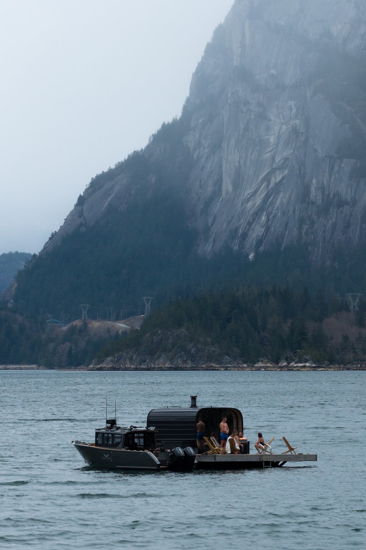 A boat beside InFlow’s floating sauna beneath the mountains