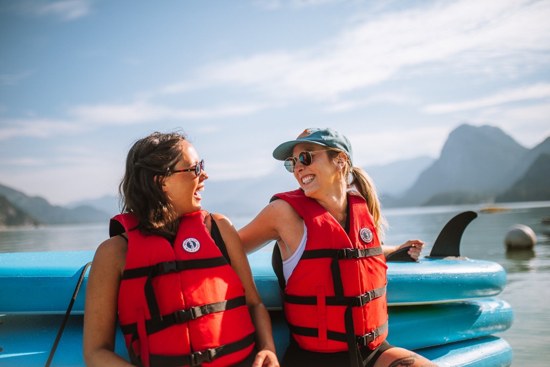 Two people wearing lifejackets beside paddleboards