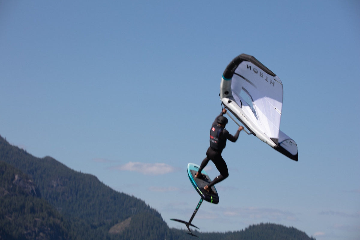 A wing foiler airborne above the water during BC Foil Fest