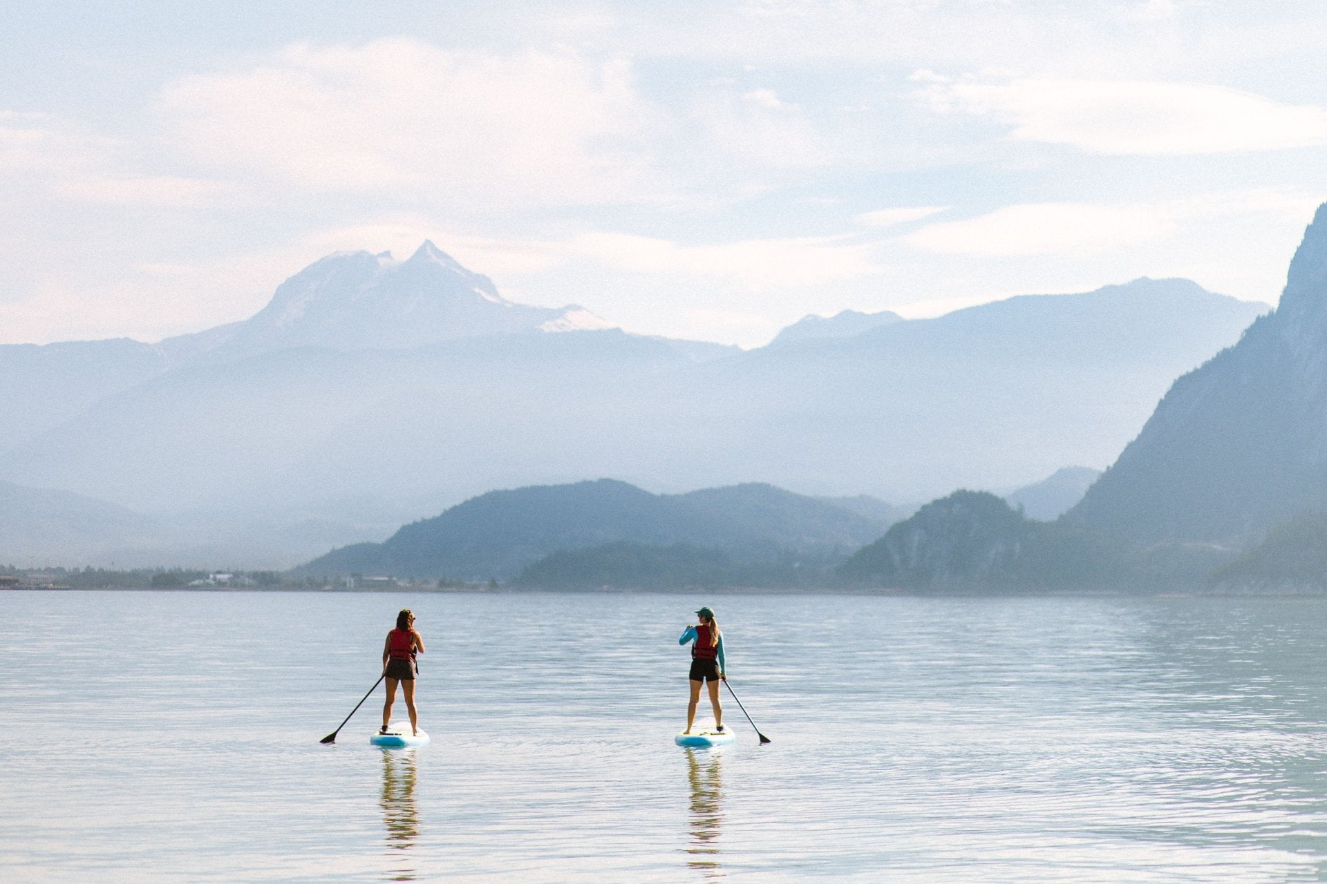 Two paddleboarders on Howe Sound with mountains beyond