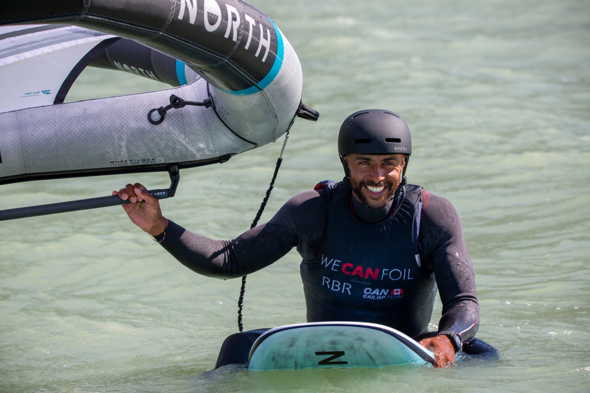 Wing foiling learner holding a wing in the water
